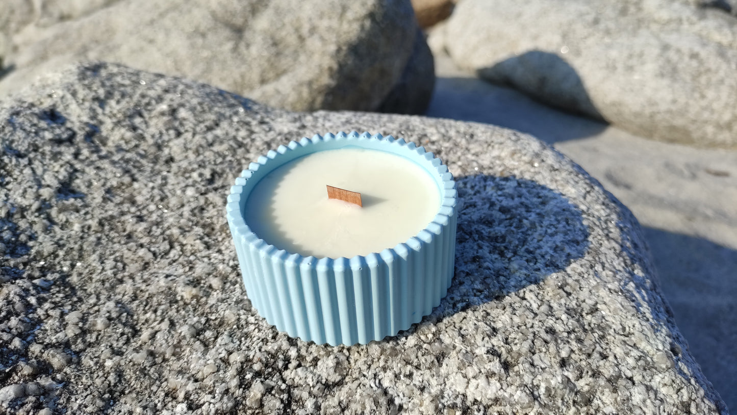 Bougie parfumée monoï dans un support rond strié bleu en jesmonite, mèche en bois