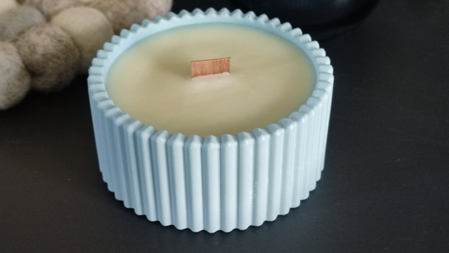 Bougie parfumée monoï dans un support rond strié bleu en jesmonite, mèche en bois