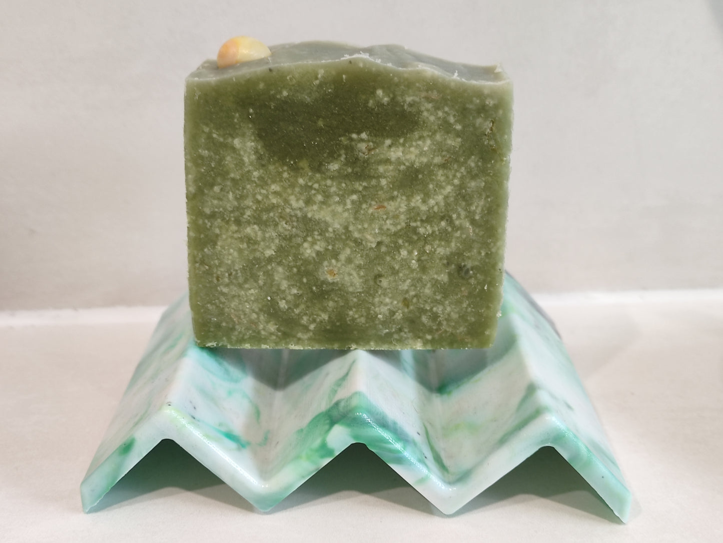 porte-savon en filet de pêche recyclé. forme en zig-zag couleur verte avec un savon posé dessus