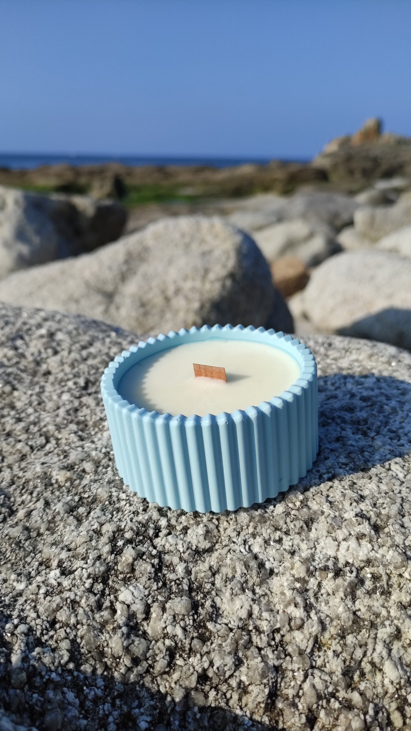 Bougie parfumée monoï dans un support rond strié bleu en jesmonite, mèche en bois