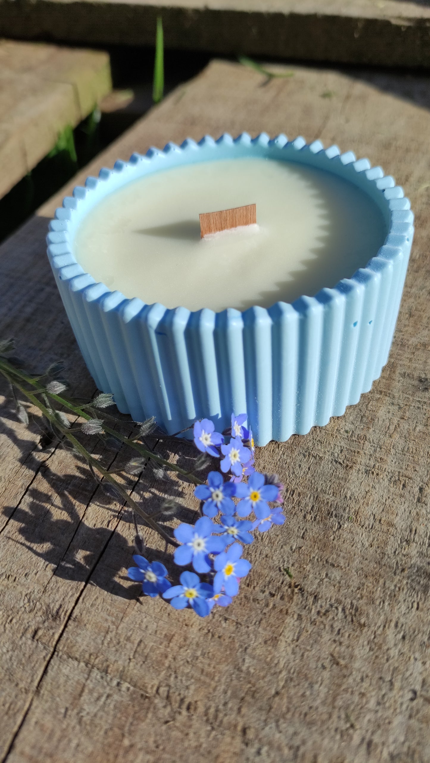 Bougie parfumée monoï dans un support rond strié bleu en jesmonite, mèche en bois