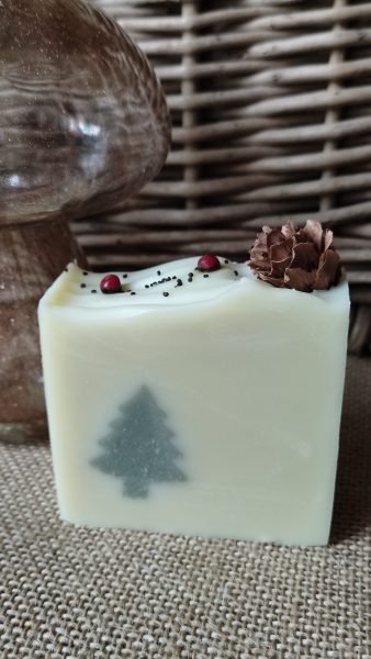 savon couleur crème avec insert sapin vert et avec petite pomme de pin sur le dessus et baies roses et graines de pavot - édition 2023