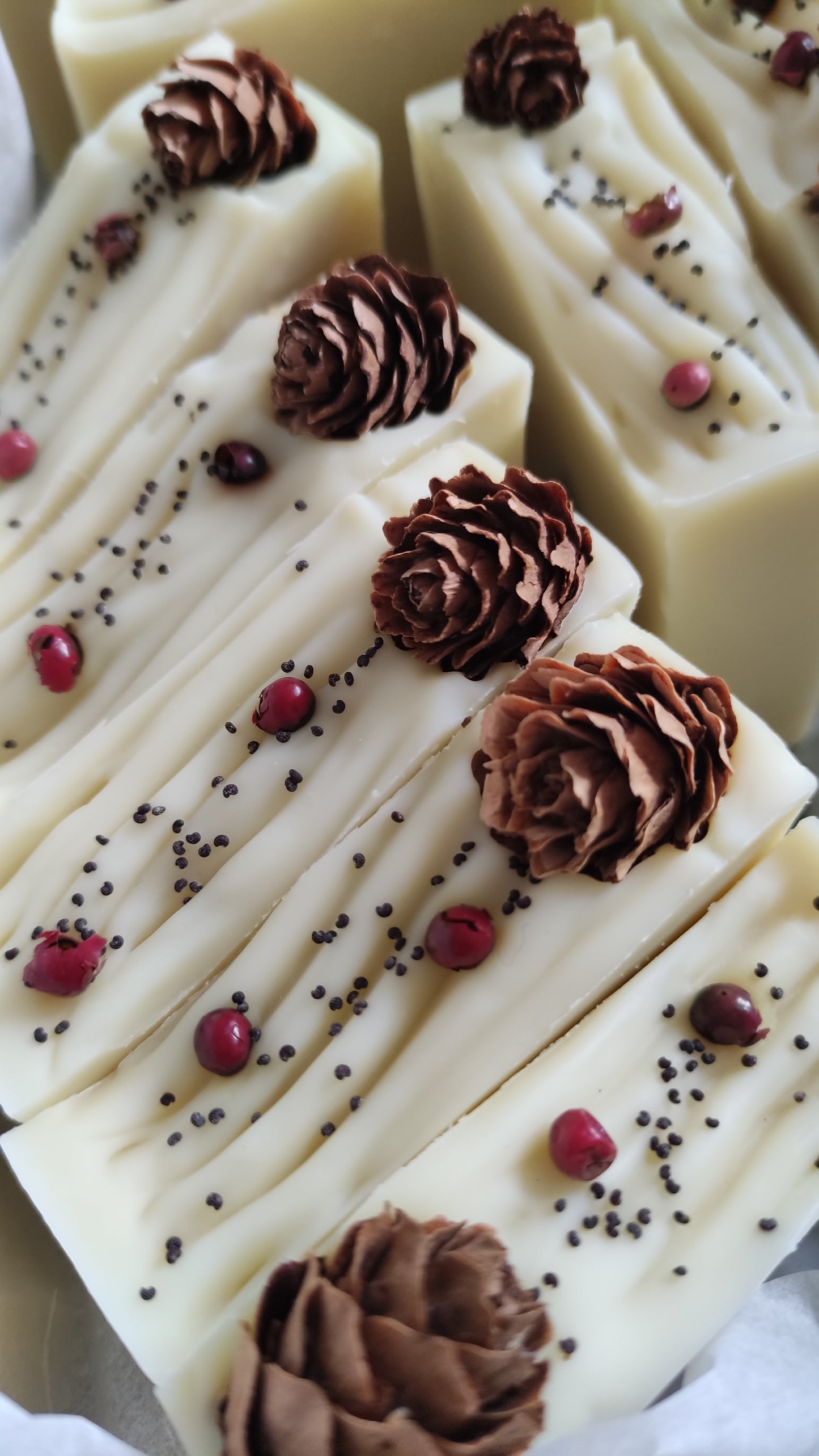 savon couleur vert pâle avec petite pomme de pin sur le dessus et baies roses et graines de pavot - vue du dessus