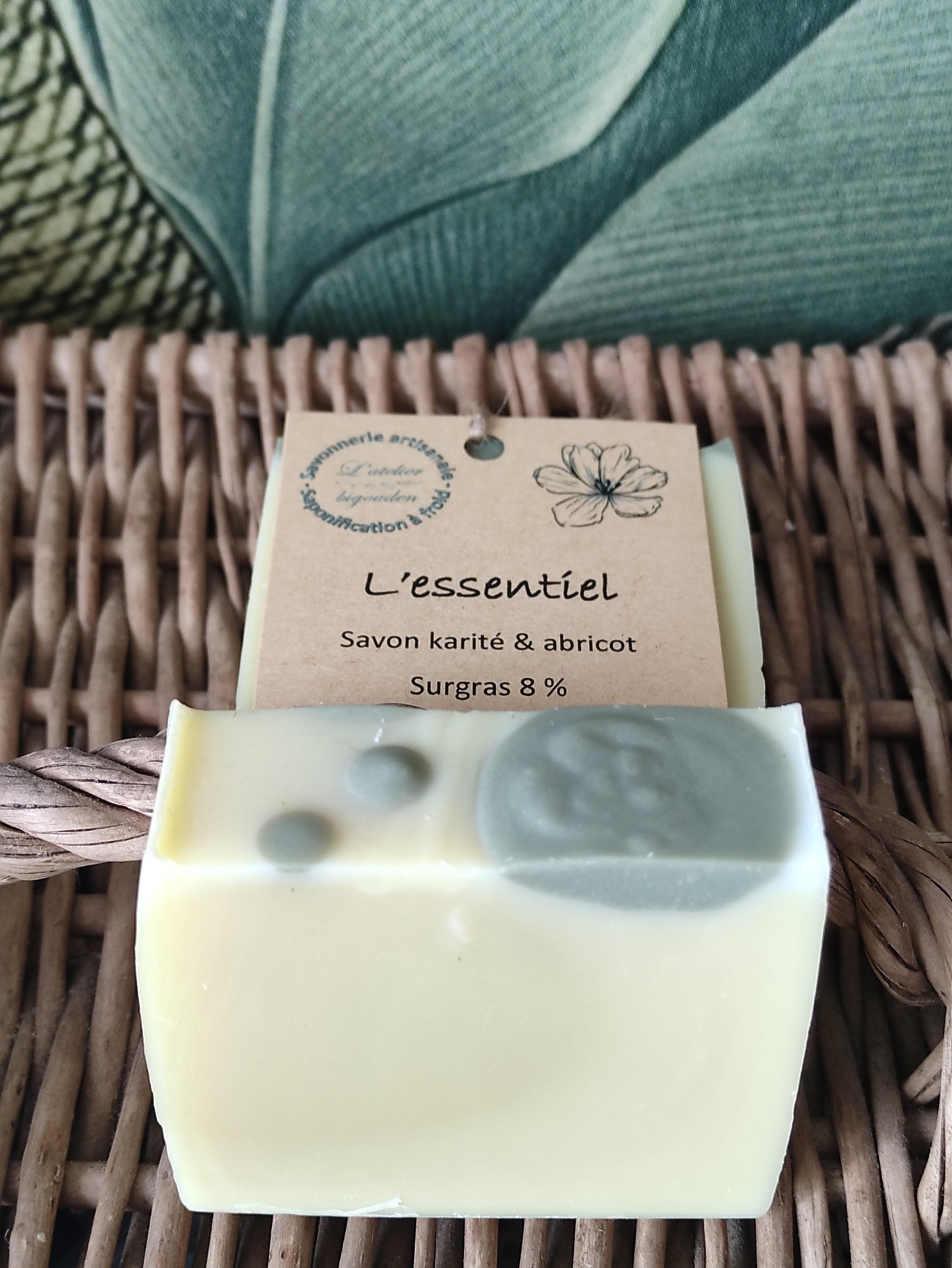 savon couleur crème avec marbrures vertes sur le dessus présenté avec et sans étiquette sur un panier en osier ancien