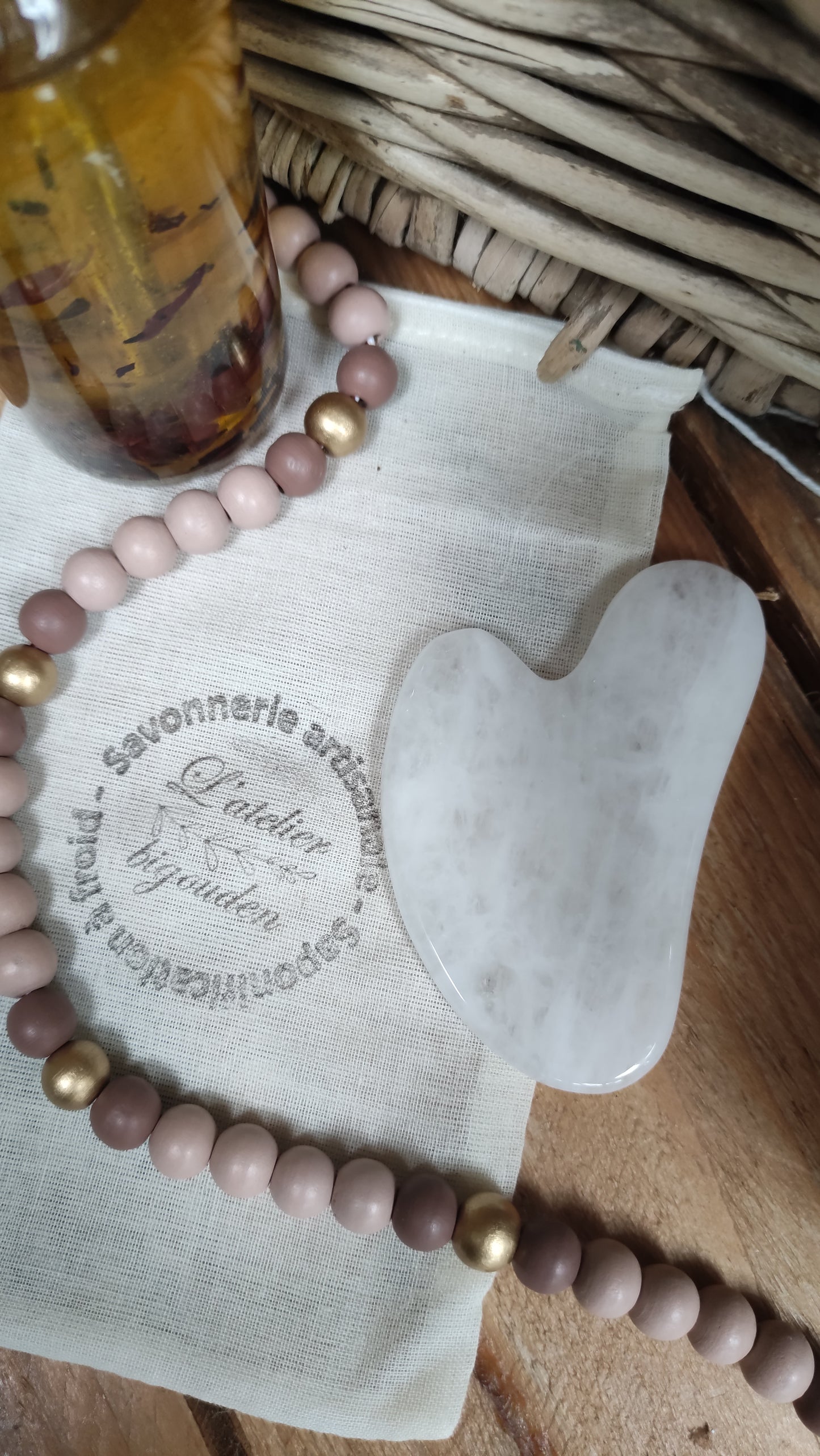 pierre plate de quartz rose en forme de coeur présentée avec une huile visage au macérât de fleurs