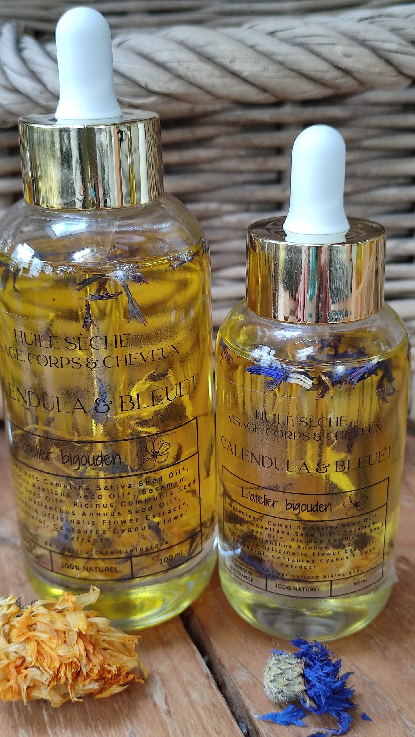 joli flacon en rondeur, transparent avec un bouchon compte-goutte doré. L'huile est jaune or avec des étale de fleurs de calendula et de bleuet en suspension.