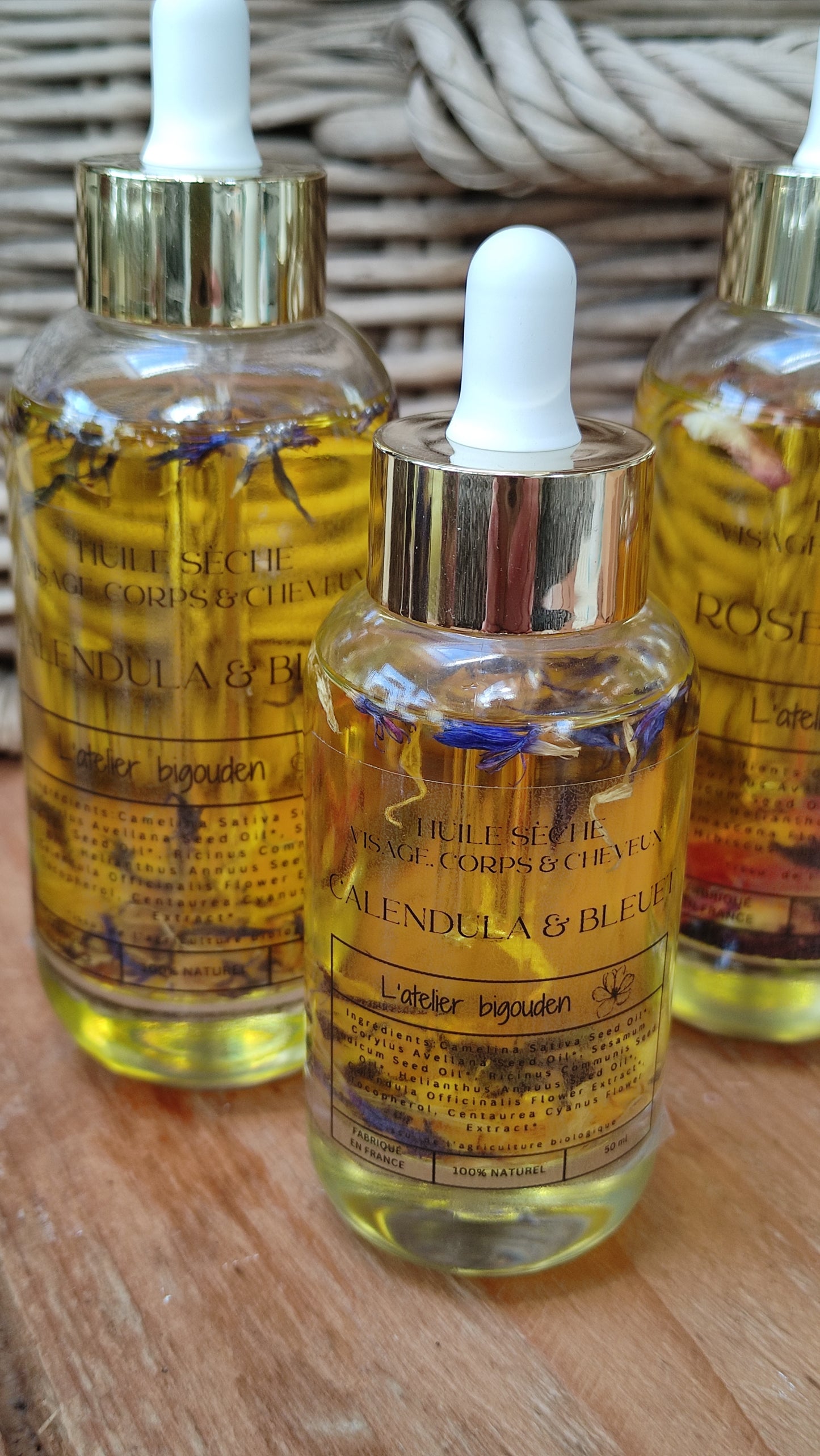 joli flacon en rondeur, transparent avec un bouchon compte-goutte doré. L'huile est jaune or avec des étale de fleurs de calendula et de bleuet en suspension.