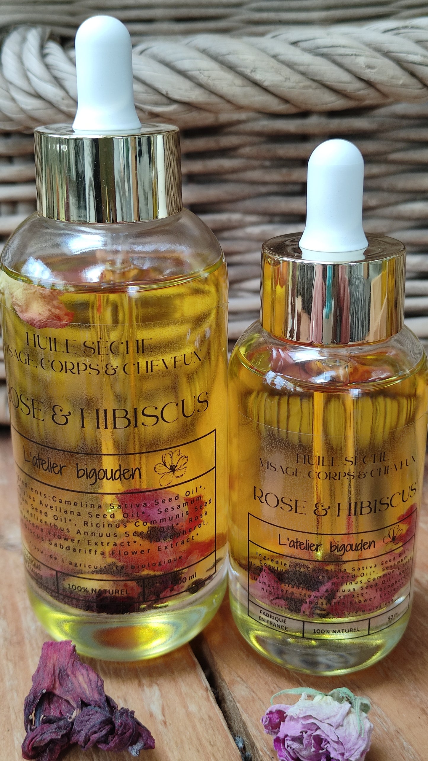 joli flacon en rondeur, transparent avec un bouchon compte-goutte doré. L'huile est jaune or avec des étale des pétales de rose et des fleurs d'hibiscus en suspension.