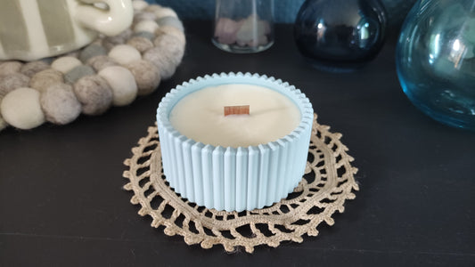 Bougie parfumée monoï dans un support rond strié bleu en jesmonite, mèche en bois