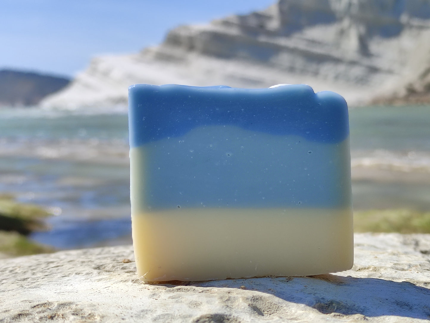 Savon saponifié à froid avec des dégradés bleus et blancs rappelant la mer. Un coquillage blanc est posé dessus