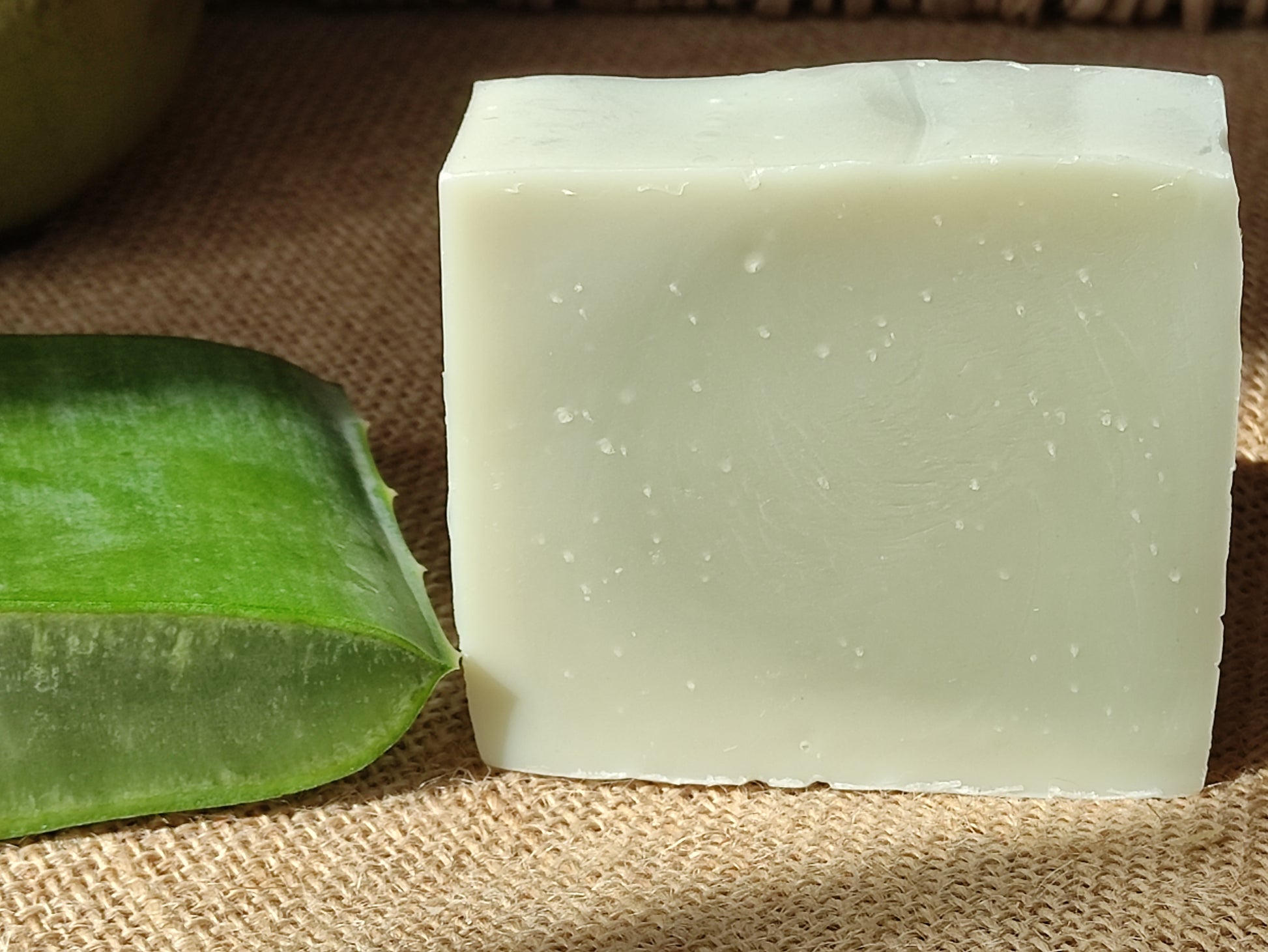 savon vert pâle à côté d'un tronçon d'une feuille fraiche d'aloe vera