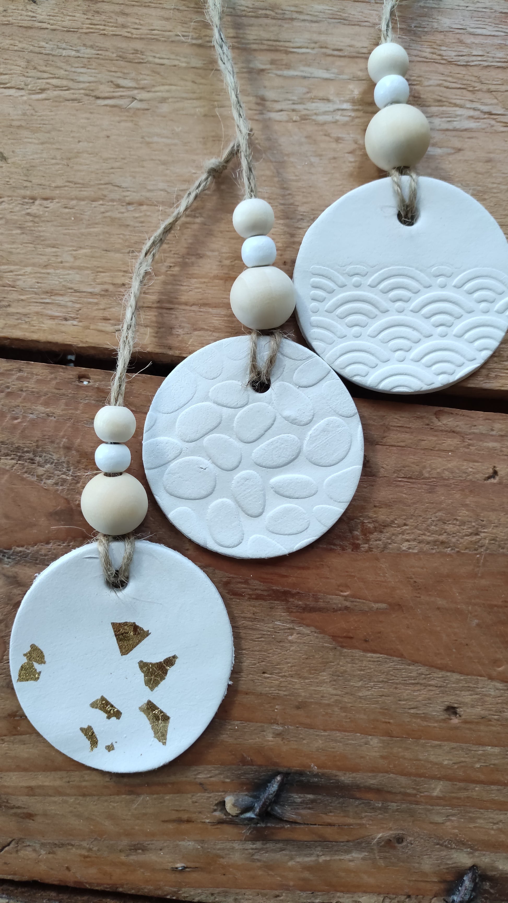 suspension ronde en argile blanche  soutenue par une ficelle de chanvre avec 3 perles de bois aux tons naturels