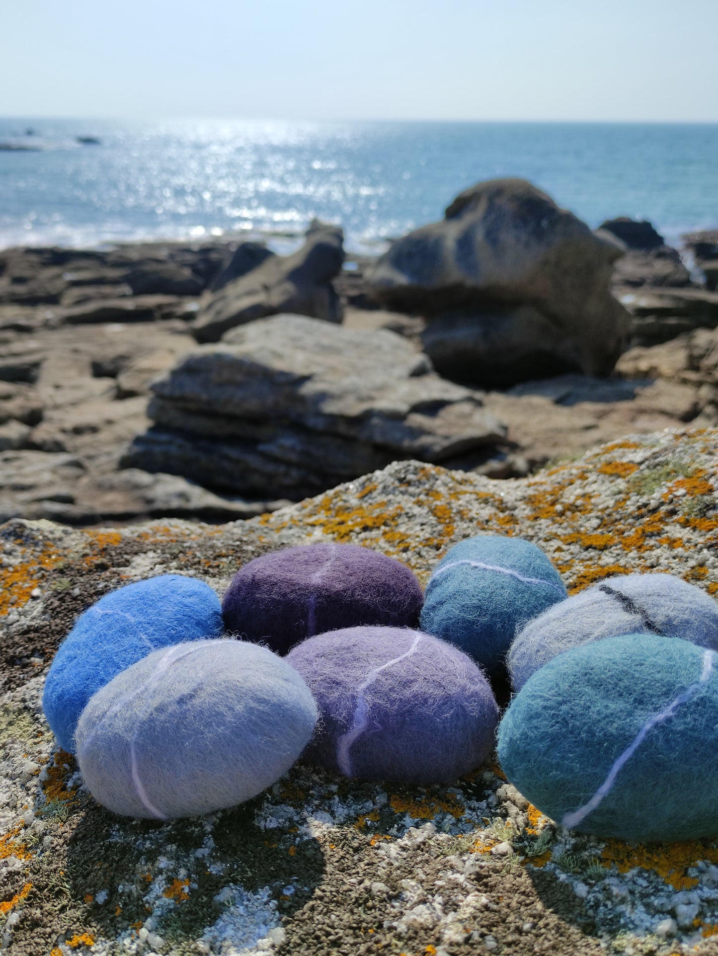 savons galets en laine feutrée posés sur des rocher en bord de mer