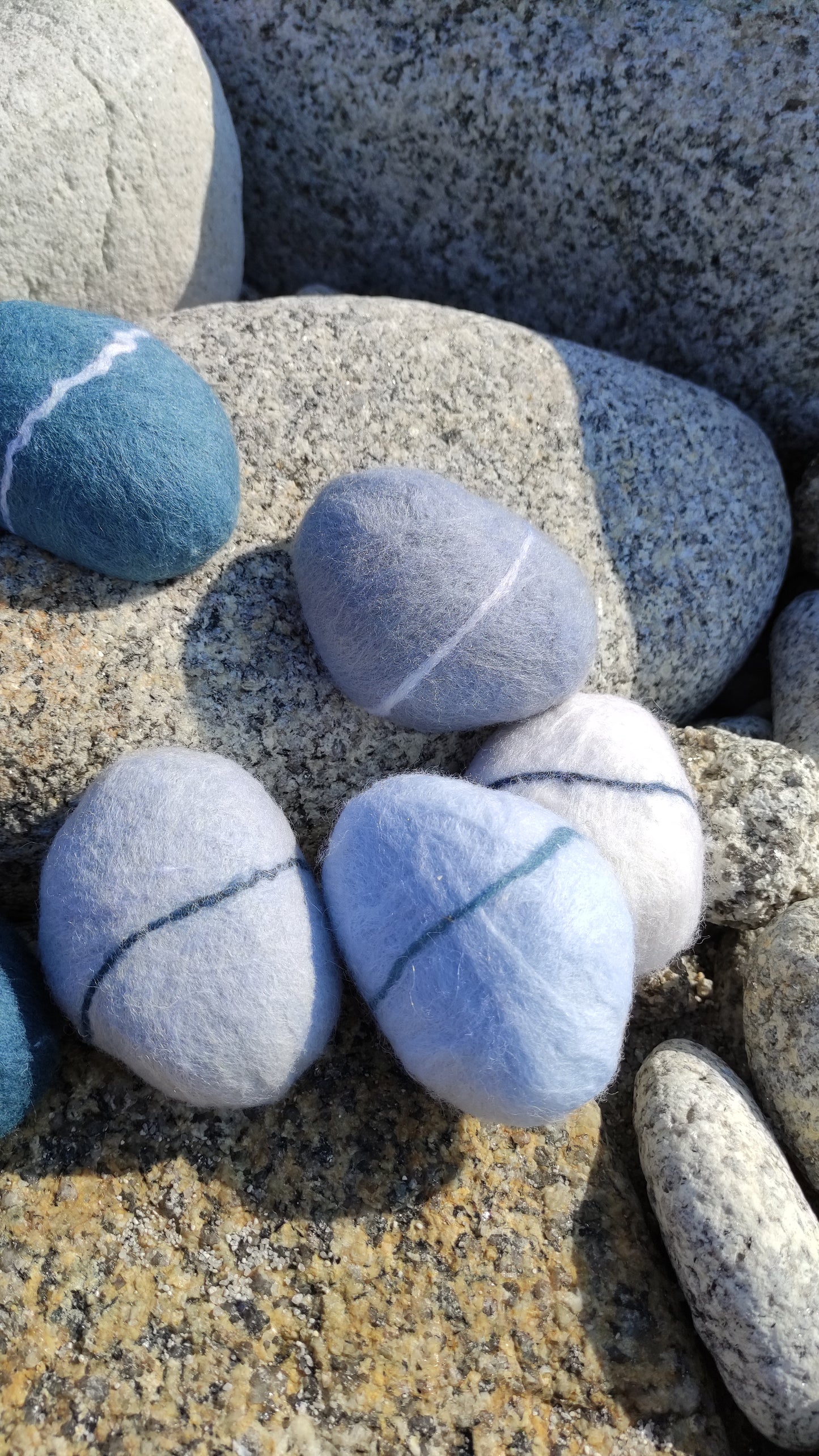 savon saponifié à froid, galet en laine feutrée posés sur des rochers de granit