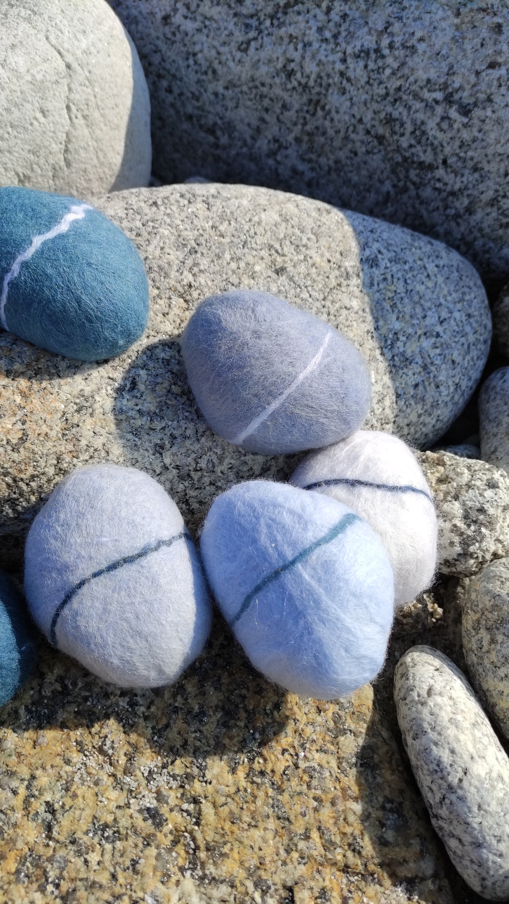 savon saponifié à froid, galet en laine feutrée posés sur des rochers de granit