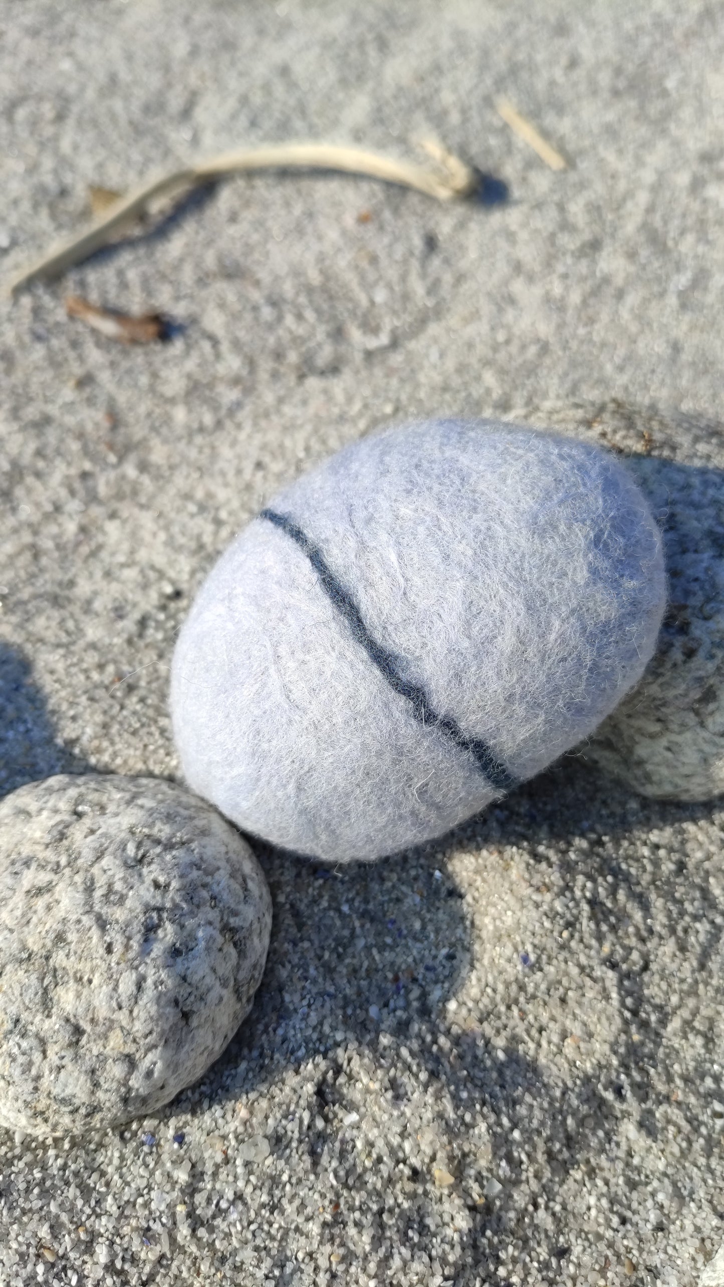 savon saponifié à froid, savon en laine feutrée imitant un galet posé sur le sable