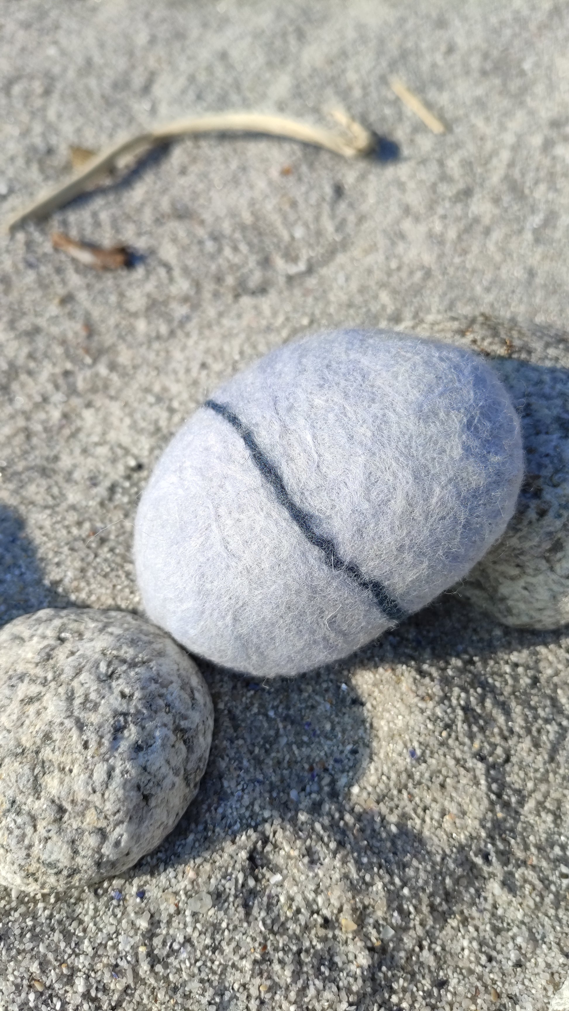 savon saponifié à froid, savon en laine feutrée imitant un galet posé sur le sable