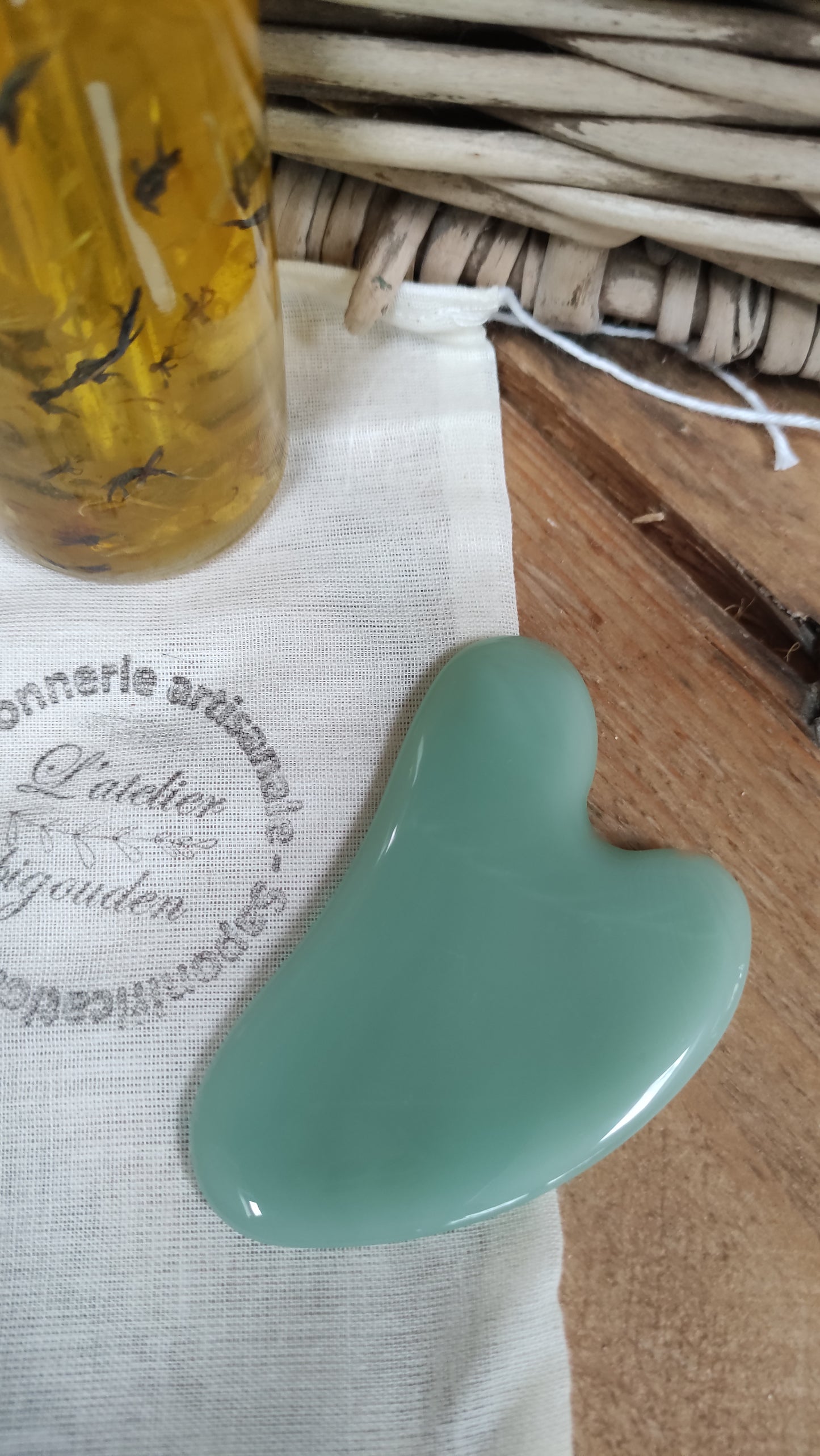 pierre plate d'aventurine en forme de coeur présentée avec une huile visage au macérât de fleurs